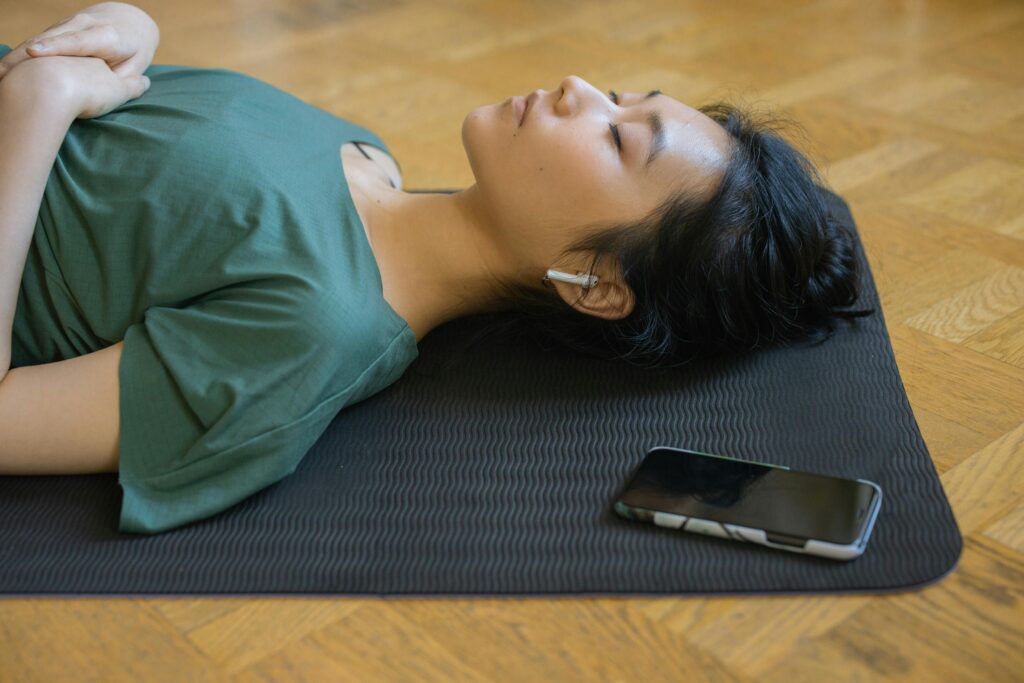 Person sitting comfortably with eyes closed, using a meditation app for nervous system regulation.