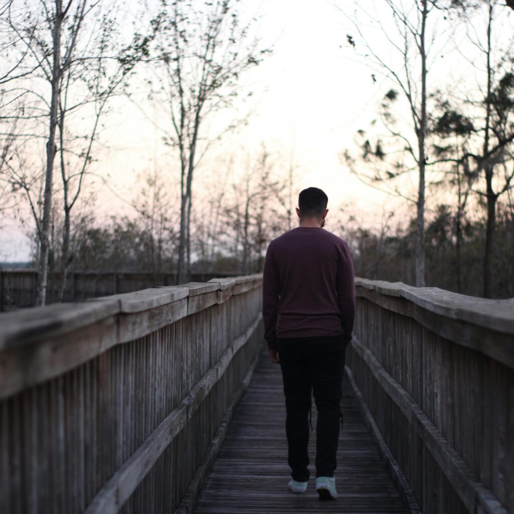 Person walking alone outdoors, using movement to regulate their nervous system after conflict.