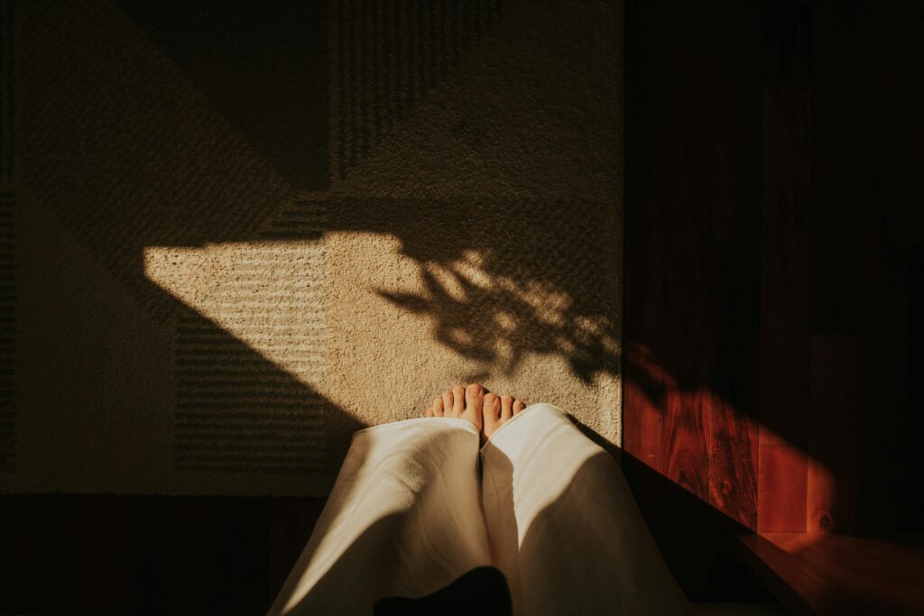 Person sitting with bare feet on the floor, practising somatic grounding for anxiety.