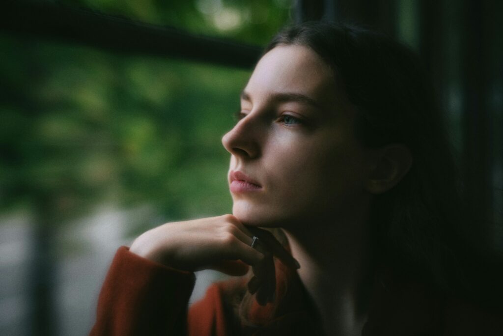 Person sitting quietly in a reflective moment, looking out a window.