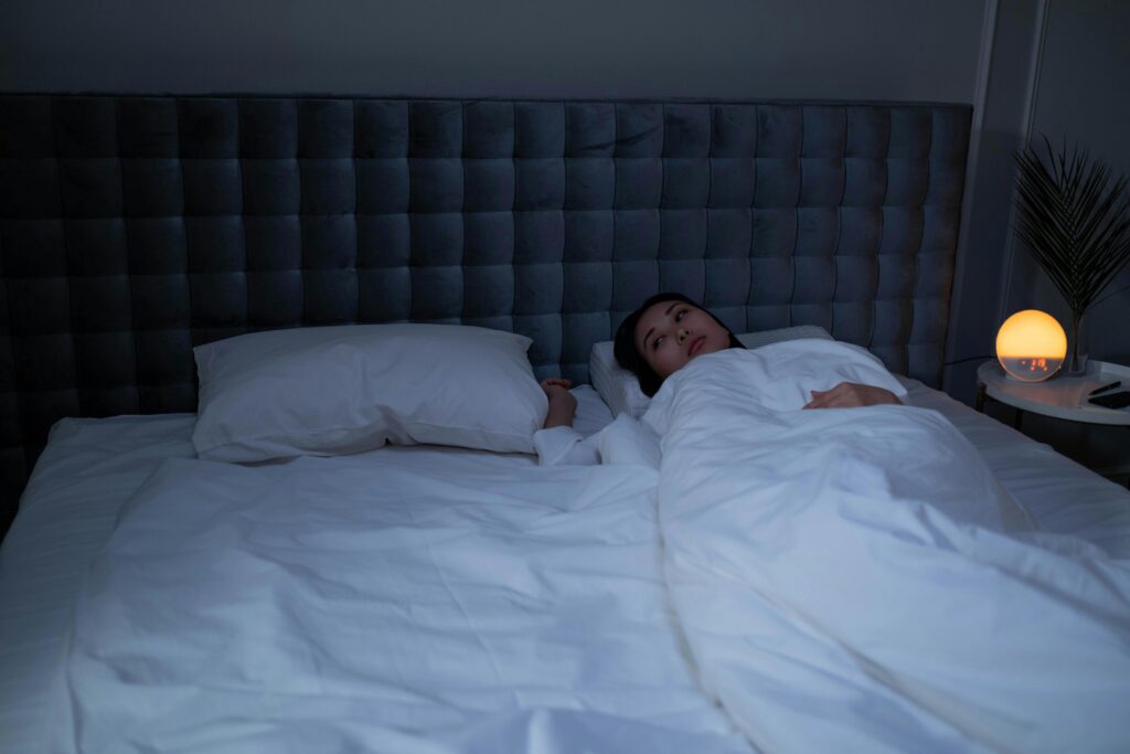 Person lying awake at night, nervous system too activated to sleep.