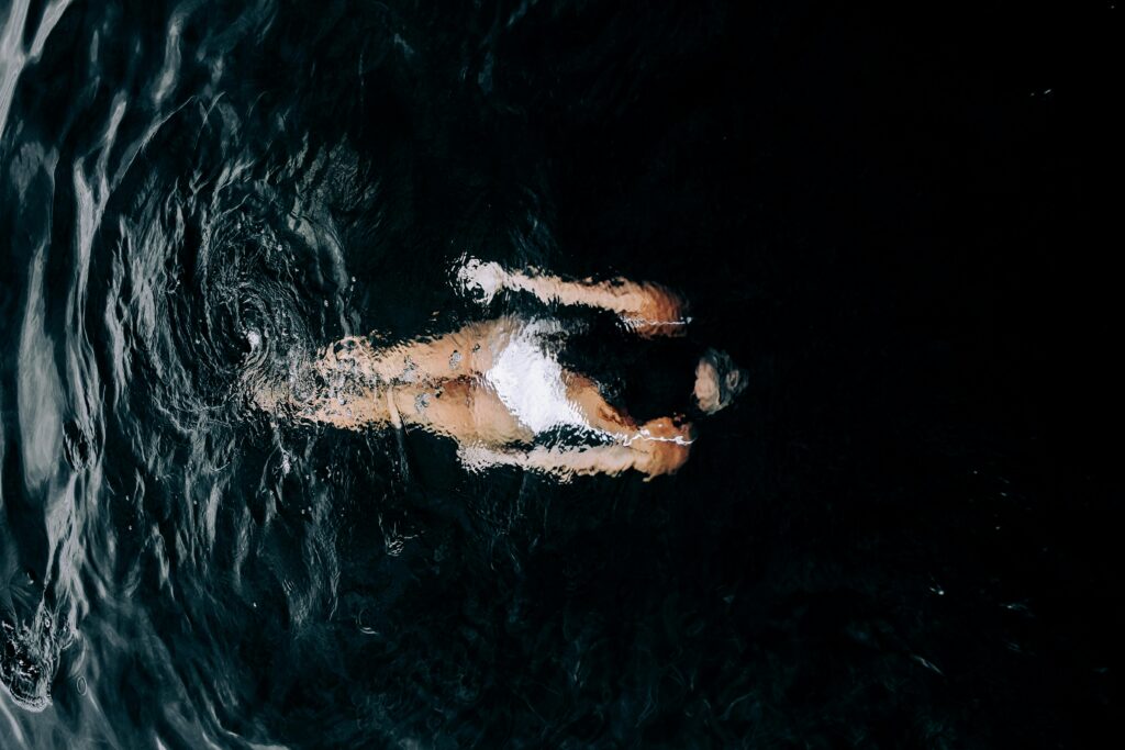 Person swimming in cold open water, using cold water therapy for nervous system health.